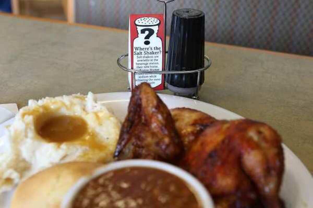 A sign explaining the absence of salt shakers is posted on a table inside a Boston Market restaurant.