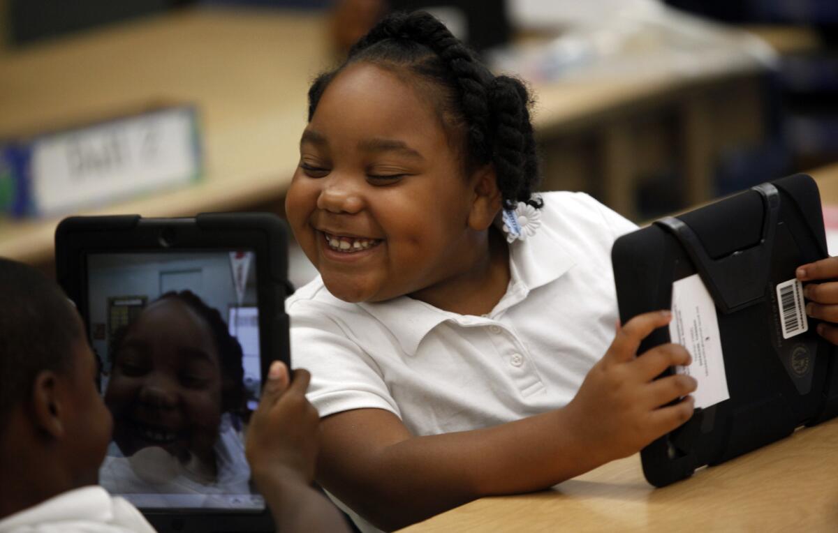 Tiannah Dizadare gives a big smile to schoolmate Avery Sheppard as they explore their new LAUSD-provided iPads at Broadacres Elementary School.