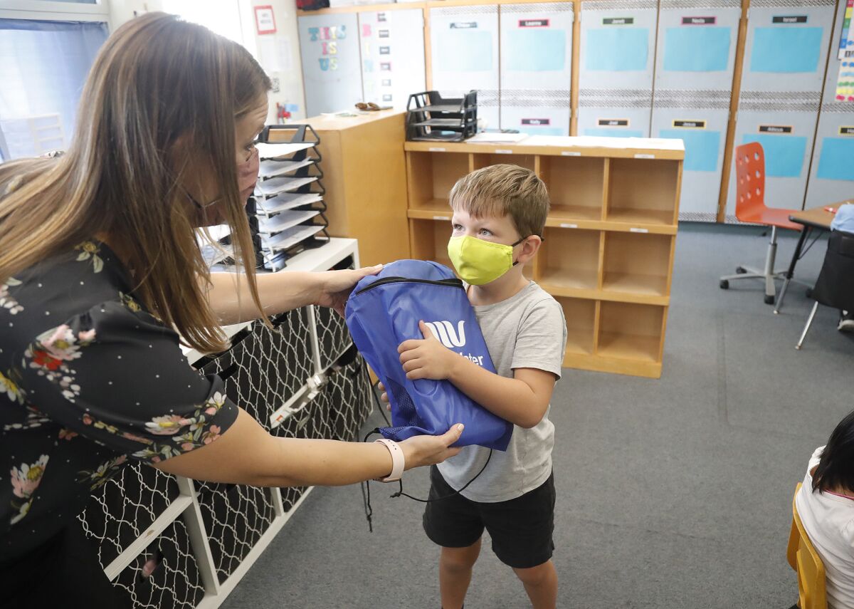 A first-grader in Rebekah Lefler's class at Paularino Elementary accepts a backpack of school supplies Wednesday. 