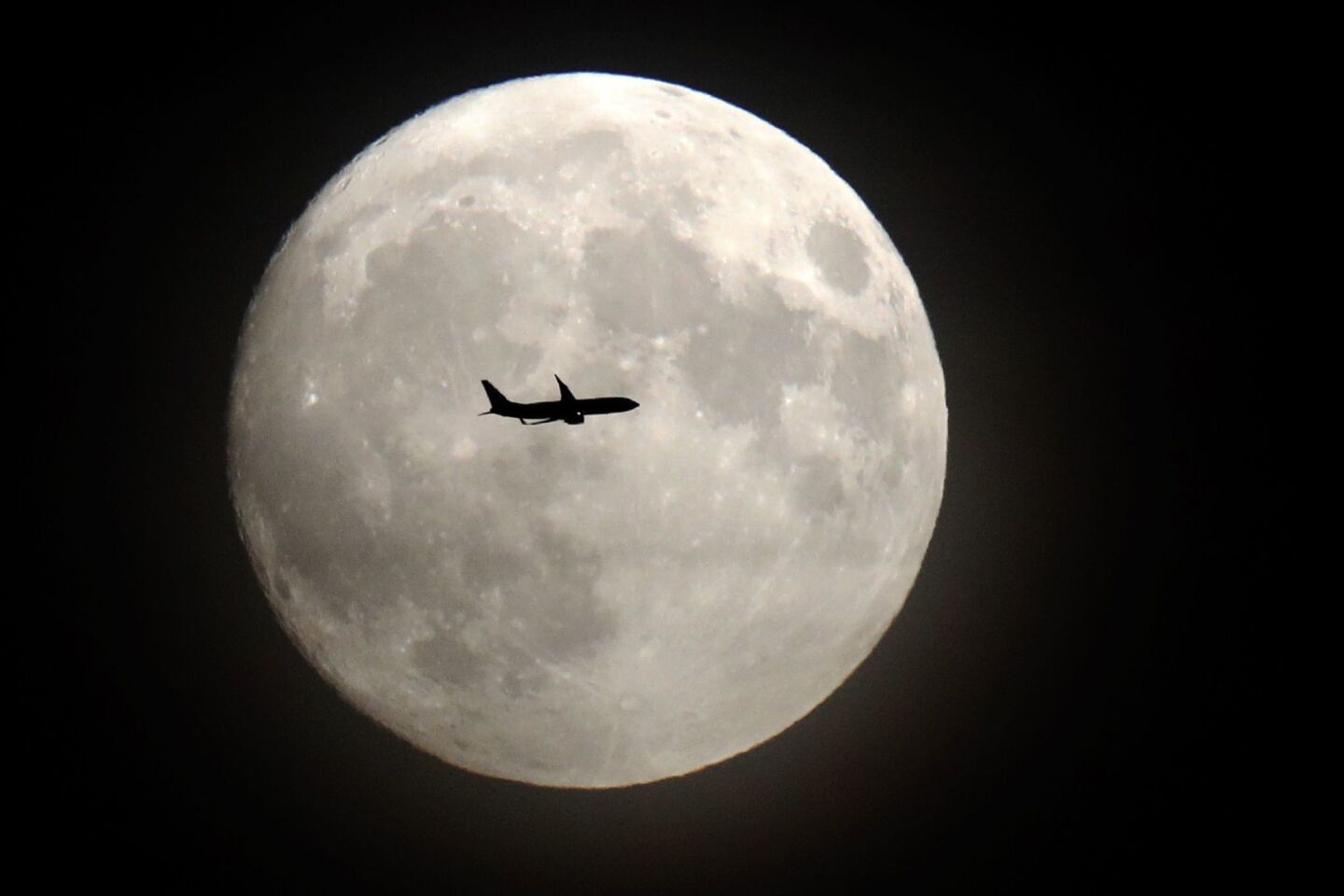 A commerical jet flies in front of the moon on its approach to Heathrow airport in London.