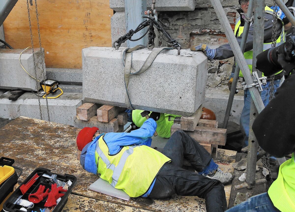 Massachusetts officials work to remove a time capsule from the cornerstone of a Boston statehouse. The relic is believed to contain items such as old coins and newspapers.