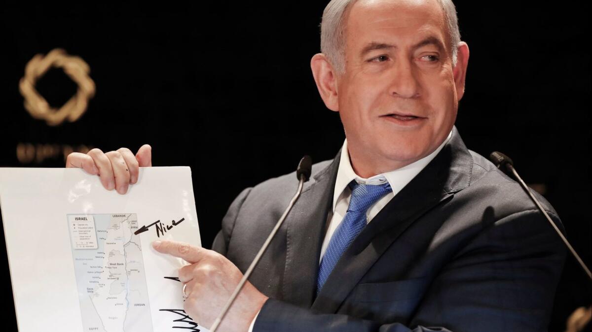 Israeli Prime Minister Benjamin Netanyahu, speaking May 30 to the media, points to the Golan Heights on a map of Israel featuring a note and signature from President Trump.