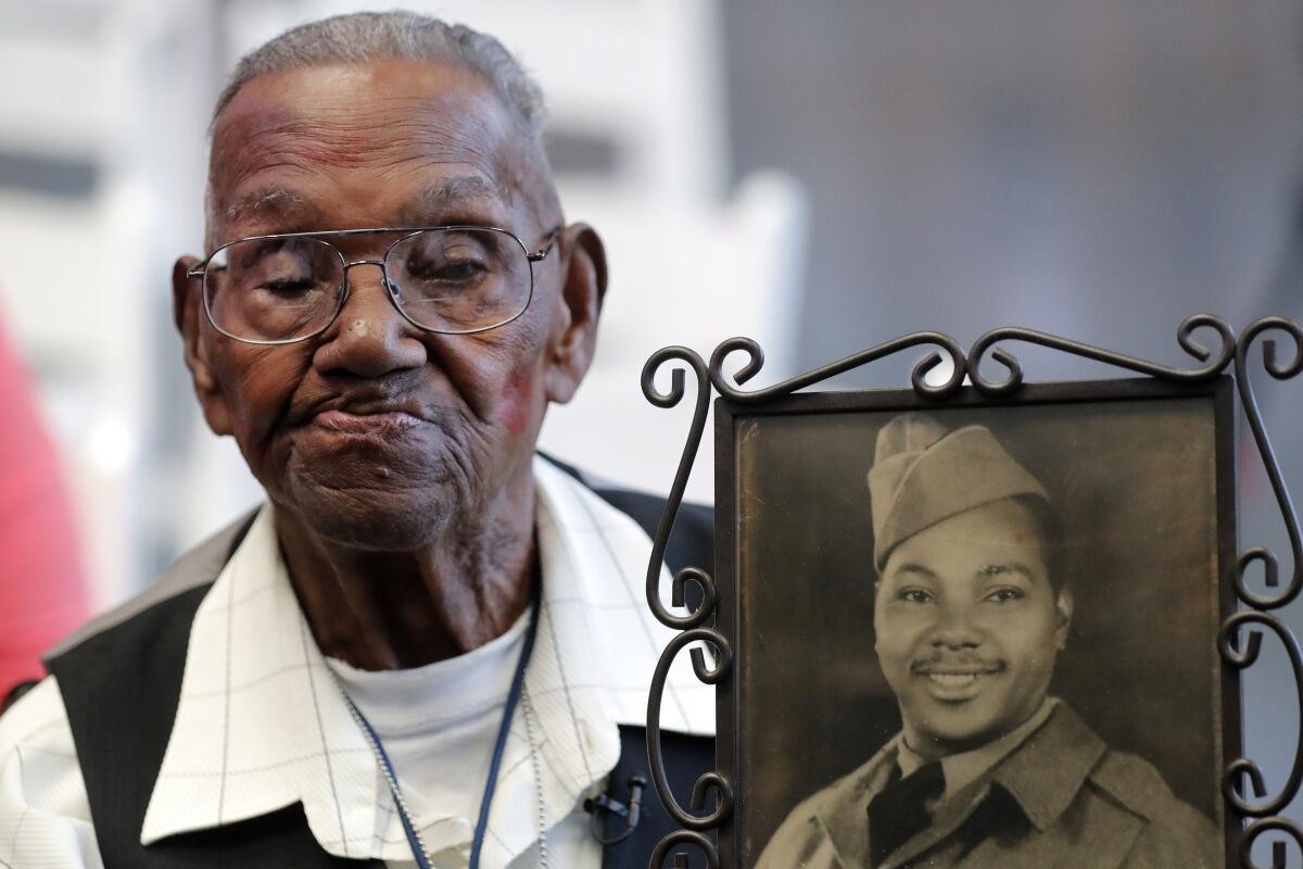 FILE - World War II veteran Lawrence Brooks holds a photo of him taken in 1943, as he celebrates his 110th birthday at the National World War II Museum in New Orleans, on Sept. 12, 2019. Brooks, the oldest World War II veteran in the U.S. — and believed to be the oldest man in the country — died on Wednesday, Jan. 5, ,2022 at the age of 112. (AP Photo/Gerald Herbert, File)
