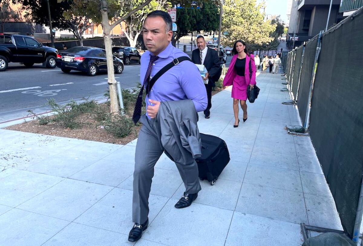 Attorney Gabriel Zendejas Chavez pulling a rolling briefcase down a sidewalk in downtown Los Angeles