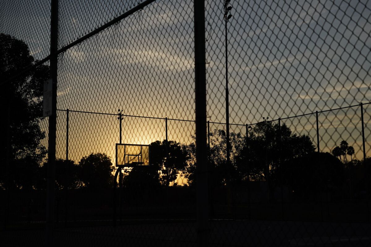 The sun sets behind a basketball backboard in a park temporarily closed due to COVID-19 in Commerce, Calif., Wednesday, Dec. 9, 2020. Thirteen counties in Northern California will be placed under the state's most restrictive coronavirus rules this week because capacity in intensive care units has fallen below 15%, and officials warned Wednesday that hospitals across the state are filling up with COVID-19 patients. (AP Photo/Jae C. Hong)