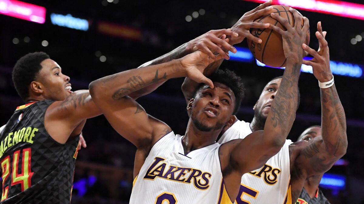 Lakers guard Nick Young tries to pull down a rebound against Hawks forward Kent Bazemore and in front of teammate Thomas Robinson during the first half Sunday.