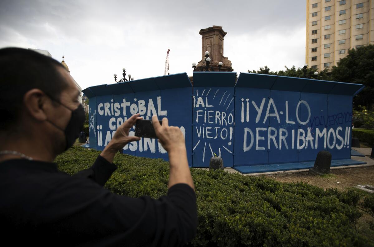 Un peatón toma una foto de un grafiti con la leyenda "Cristóbal Colón asesino