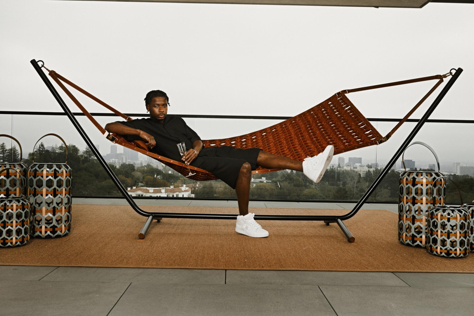 A person lies on a hammock drinking Champagne.