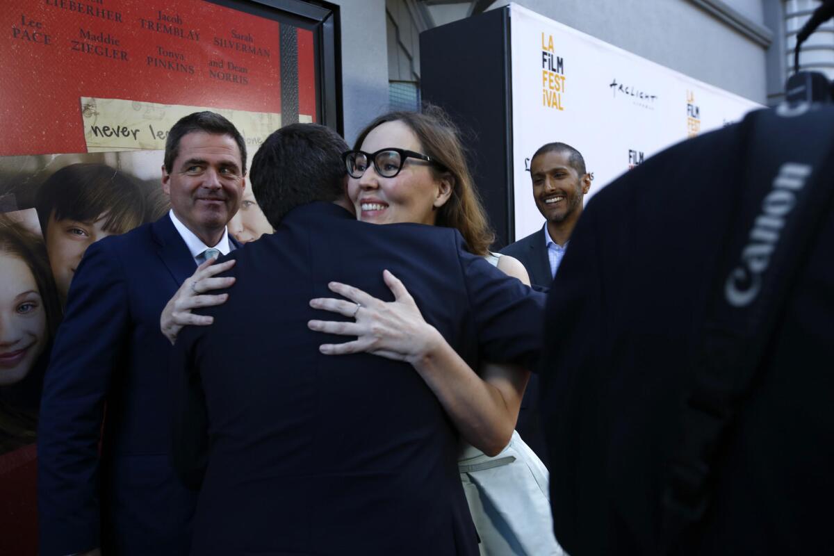 Film festival director Jennifer Cochis, right, hugs "The Book of Henry" director Colin Trevorrow as Film Independent President Josh Welsh, rear left, watches on the red carpet.