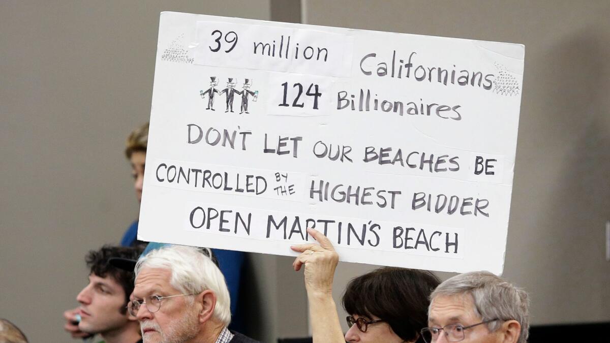 Julie Graves, a supporter of public access to Martin's Beach, displays a sign during a meeting of the State Lands Commission, in Sacramento, Calif.