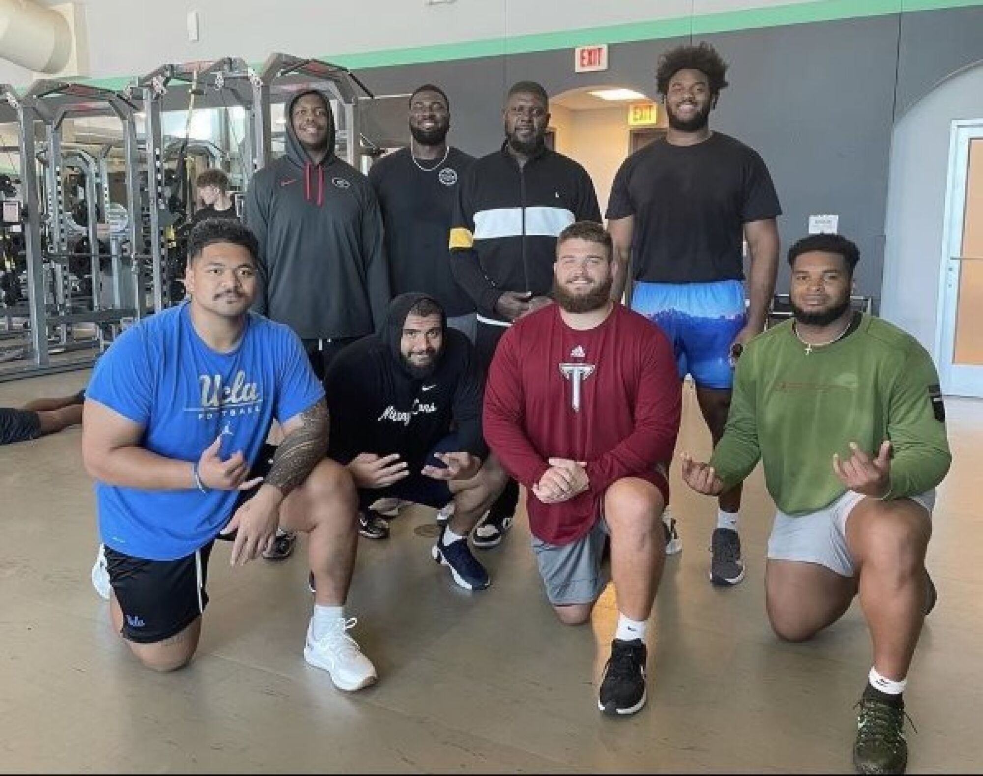 Atonio Mafi porte une chemise UCLA tout en posant avec des personnes qu'il a rencontrées lors de son entraînement pour le repêchage de la NFL.
