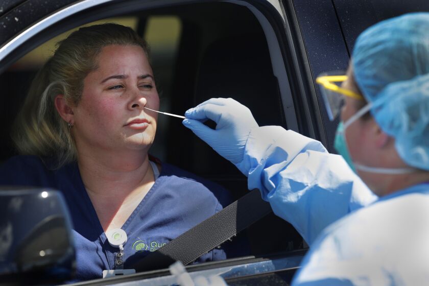 FLORIDA, USA: Nurse Jany Guedes, right, takes a sample for testing from Maria Laso at a drive-thru testing site for COVID-19, the disease caused by the new coronavirus, at the Doris Ison Health Center.