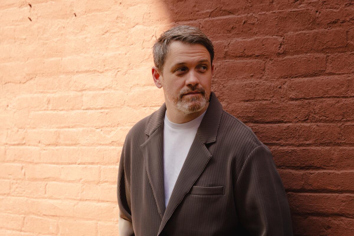 Director Michael Arden photographed against a brick wall.
