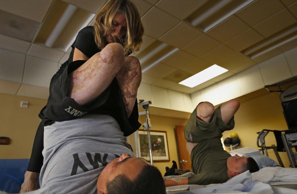Yoga instructor Sunny Keays works with Army 1st Sgt. Chris Montera, left, and Marine Pfc. Isaac Blunt at the Naval Medical Center San Diego.