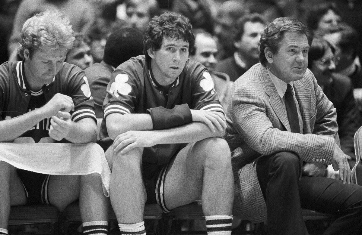 Coach Bill Fitch sits to the right of Celtics players Rick Robey, center, and Larry Bird.