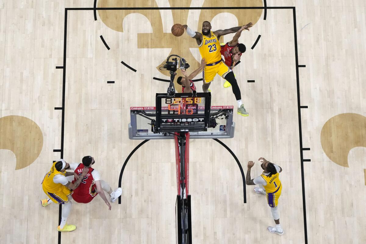 Lakers forward LeBron James shoots between Pelicans guards Trey Murphy III and CJ McCollum.