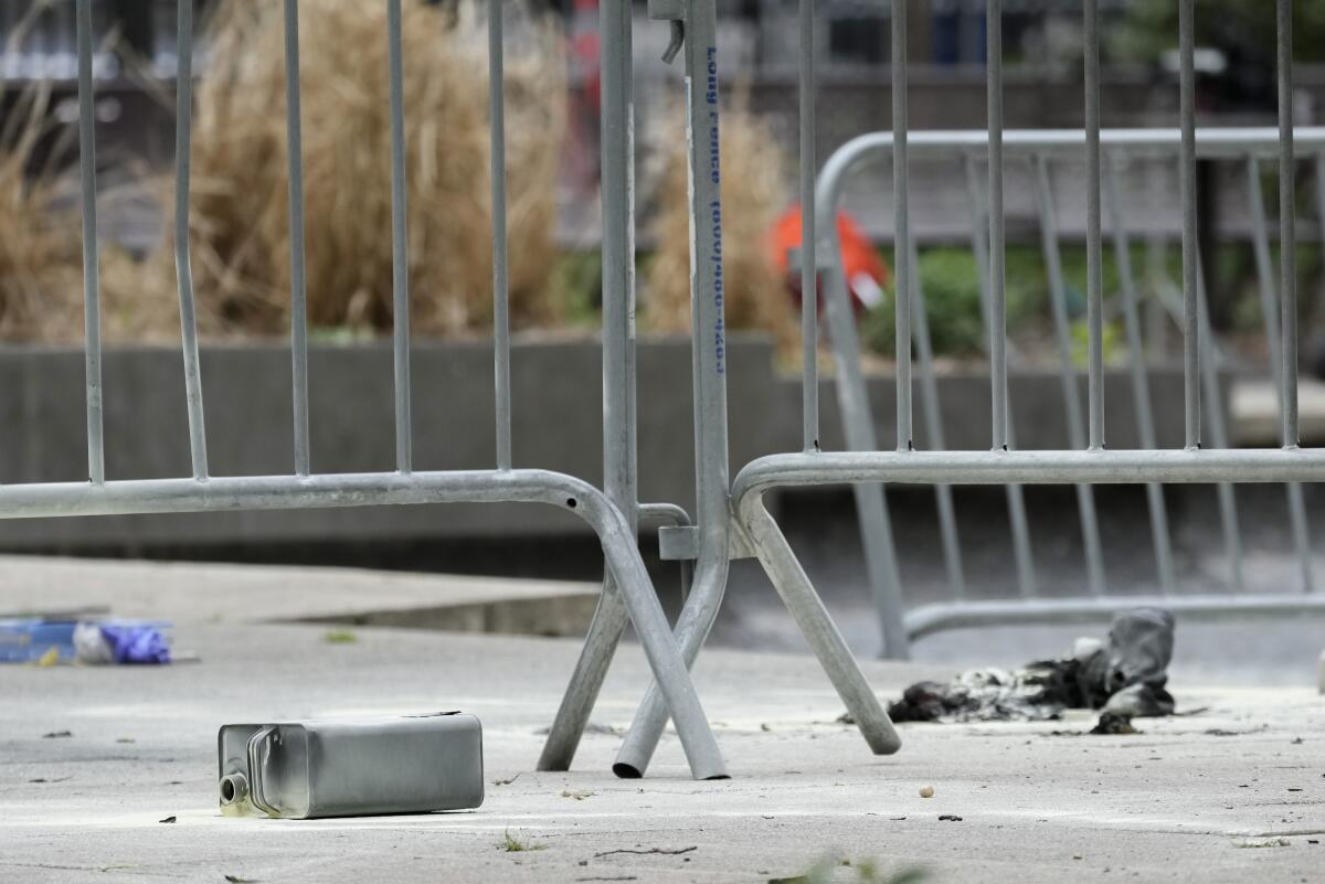 A metal can sits on the ground near metal barricades.