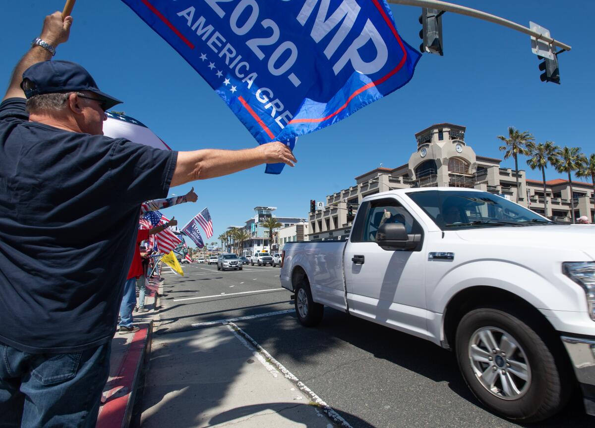 A motorist gives a thumbs up to supporters of former President Donald Trump during a rally in Huntington Beach Saturday.