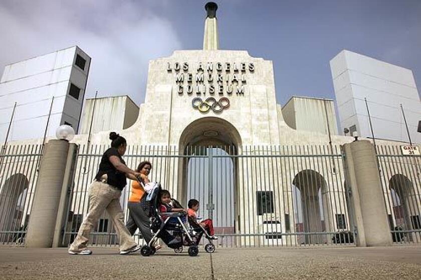 Maria Gonzales (left) walks her children with friend Victoria Guzman past the famous Los Angeles Coliseum in Exposition Park.