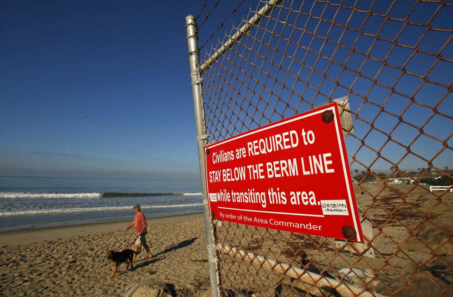 This not-so-subtle sign on a wire-topped fence reminds visitors that some of the access along San Onofre State Beach south of the Trestles surf break is restricted by the U.S. Marine Corps. There is a disagreement on whether the famed wave-riding spot should be listed on the National Register of Historic Places. Surfers say yes, the Marines say no. A state commission has sided with the surfers.