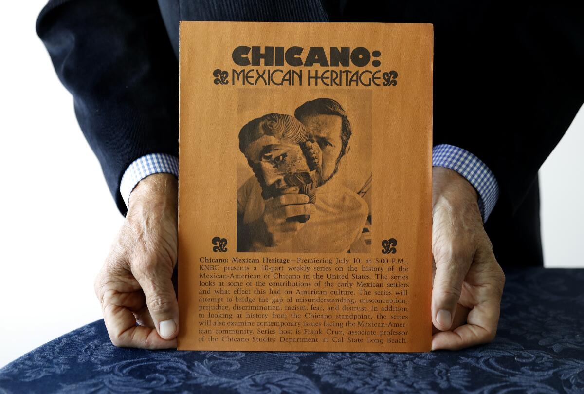Close-up of hands holding a flier promoting "Chicano I & II: The Mexican American Heritage Series."