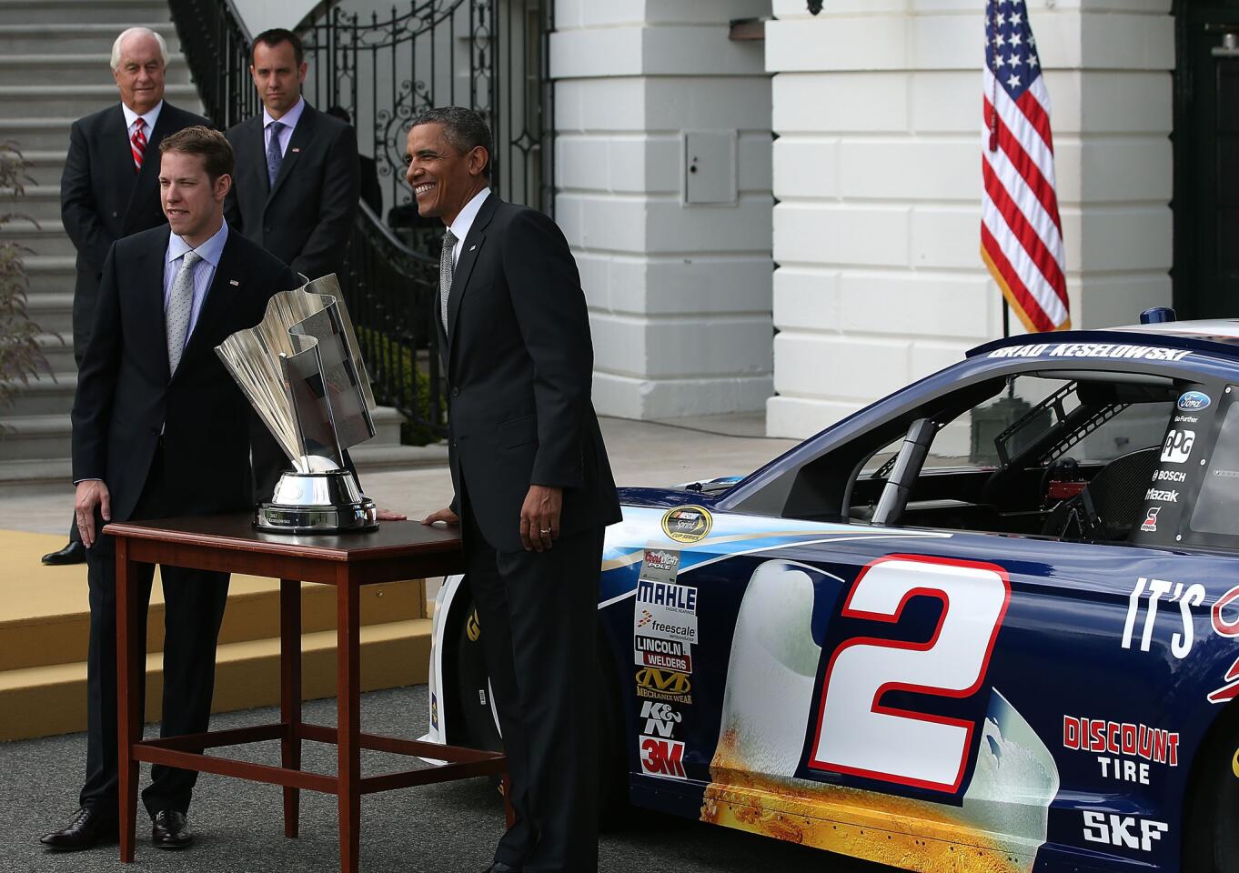 Barack Obama welcomes NASCAR Sprint Cup champion Brad Keselowski to the White House, while owner Roger Penske and crew chief Paul Wolfe stand nearby.