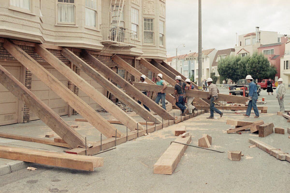 Workers use lumber to shore up a quake-damaged soft-story building in San Francisco's Marina district after the Oct. 17, 1989, Loma Prieta earthquake.