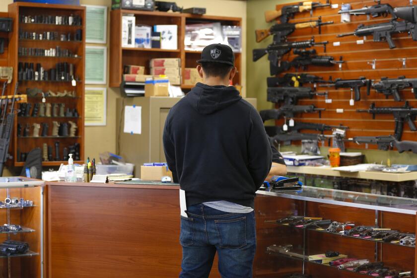 A customer shops for a gun at AO Sword Firearms in El Cajon on Thursday, March 19, 2020. David Chong, the store's owner, says that of the increase in firearm sales at his store, 90% of the business is from new gun owners.
