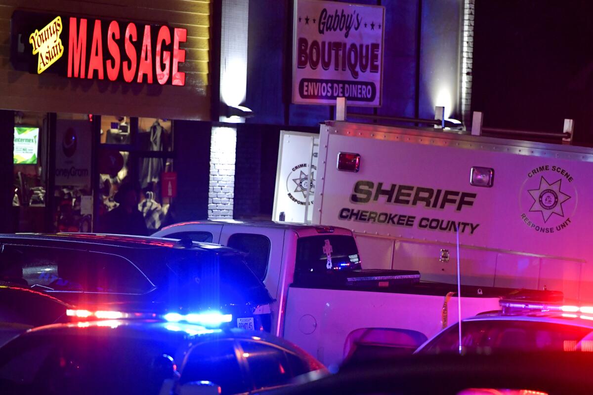 Law enforcement vehicles with lights flashing outside a massage parlor at night.