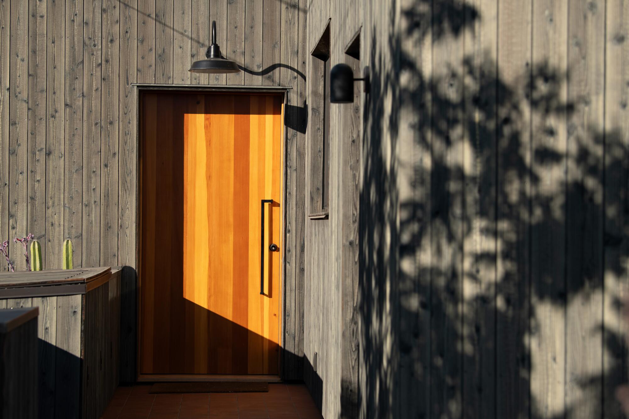 A wooden front door on a charred wood siding house