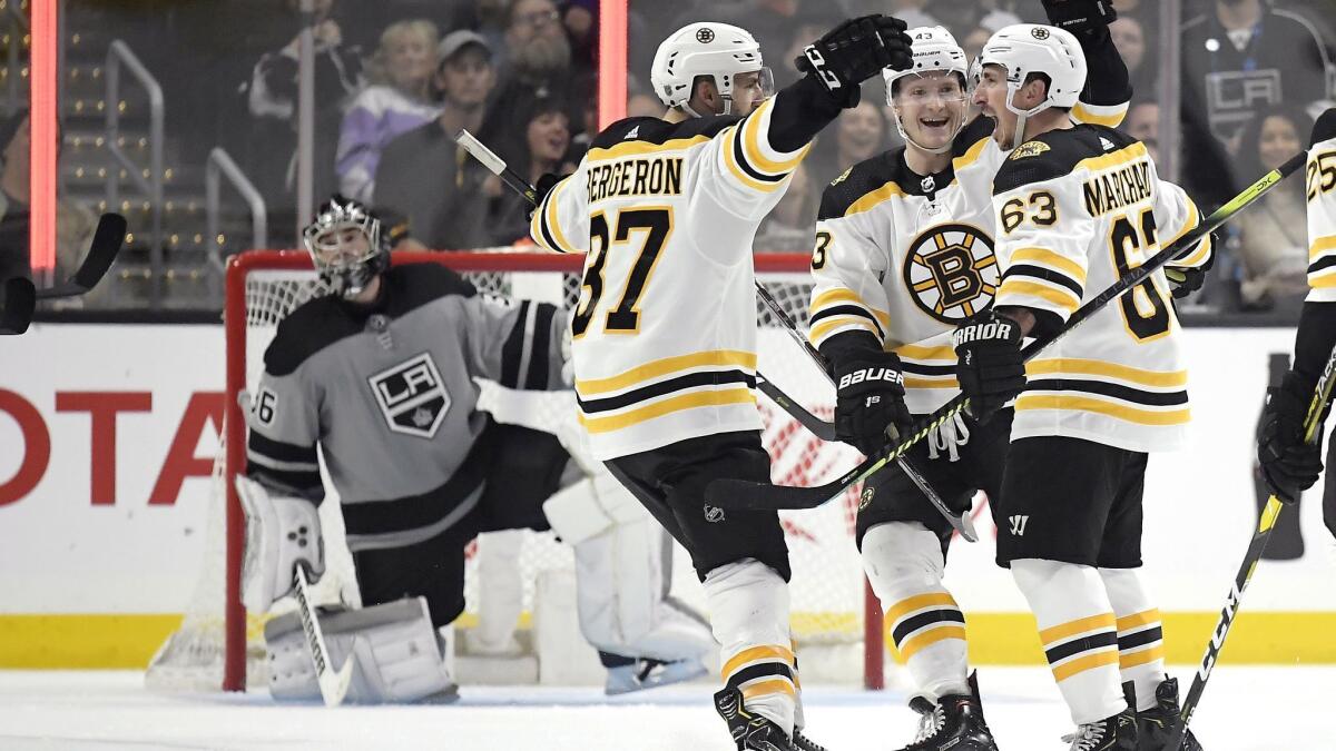 Boston Bruins forward Brad Marchand, right, celebrates with teammates Patrice Bergeron, second from left, and Danton Heinen after scoring during the second period of a 4-2 win over the Kings on Saturday.