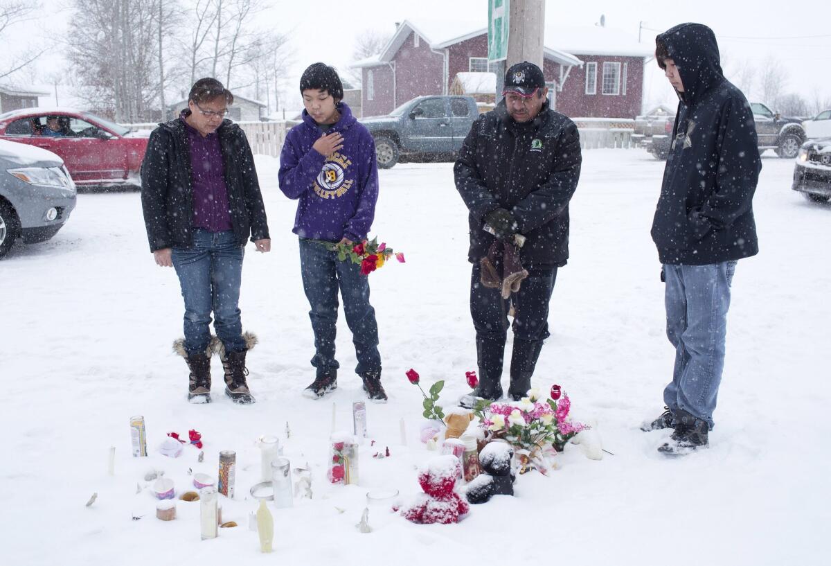A family in La Loche, Saskatchewan, pay their respects Saturday to victims of the school shooting.