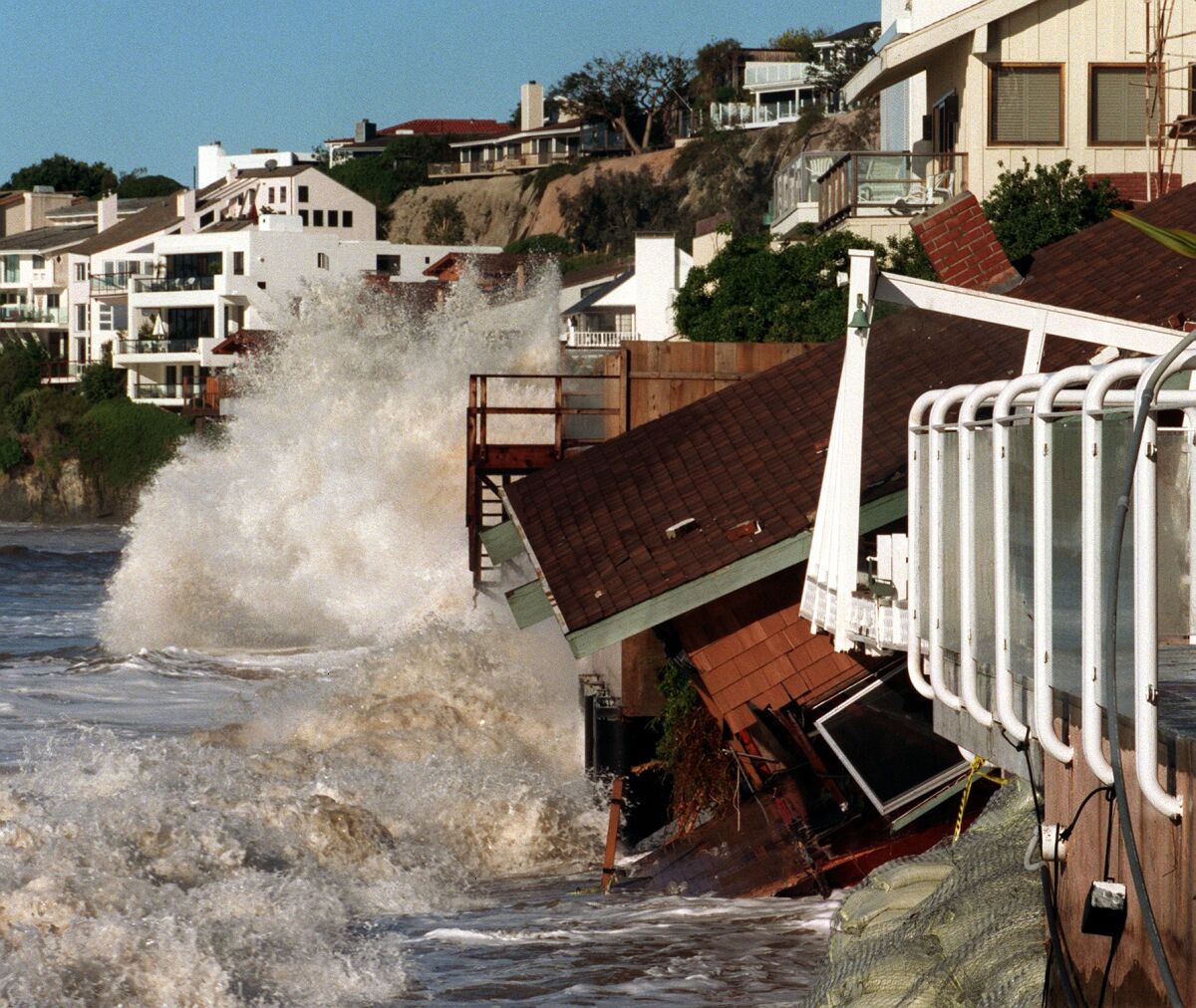 Waves crash into homes along Broad Beach in Malibu in 1998, sending one sliding toward the sea.