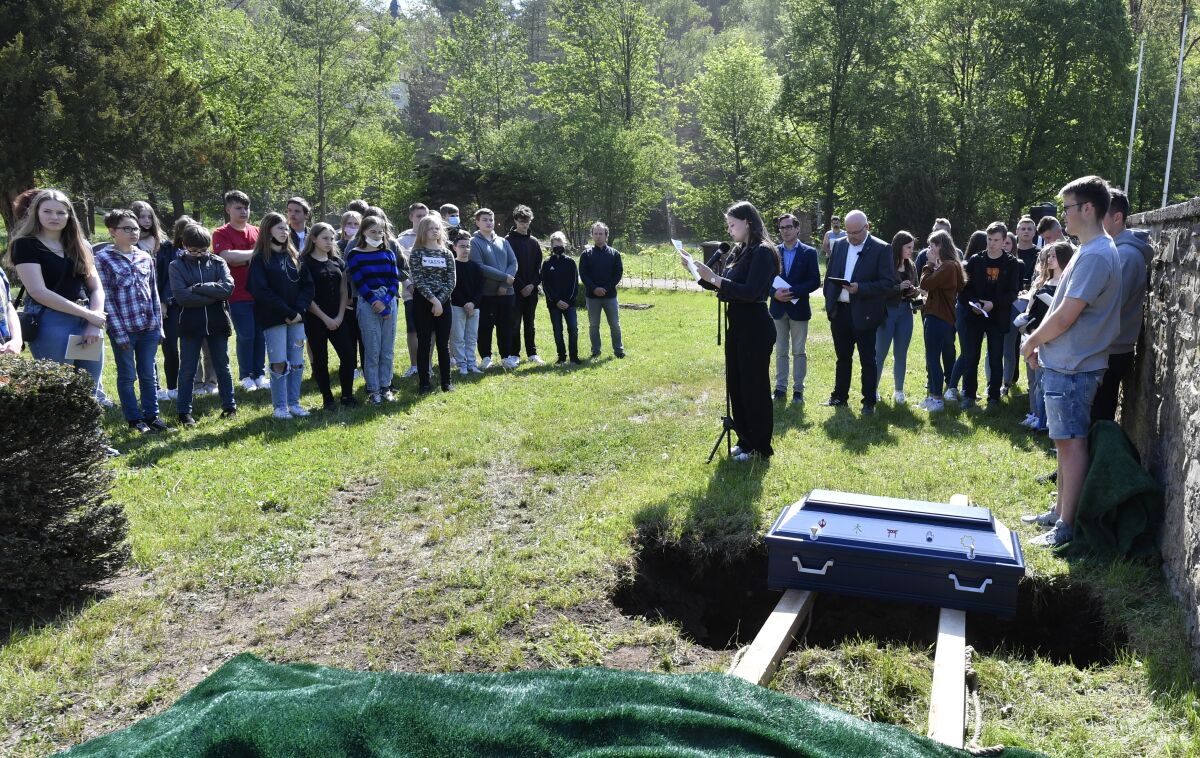 Pupils of the Johannes-Sturmius-Gymnasium say goodbye to the coffin with the bones of a school skeleton at the cemetery, where they are being buried, in Schleiden, Germany, May 11, 2022. The real skeleton of an unknown woman, christened Anh Bian by the students, had served as a visual object for the students in biology classes since 1952. It has since been replaced by a plastic model. (Roberto Pfeil/dpa via AP)