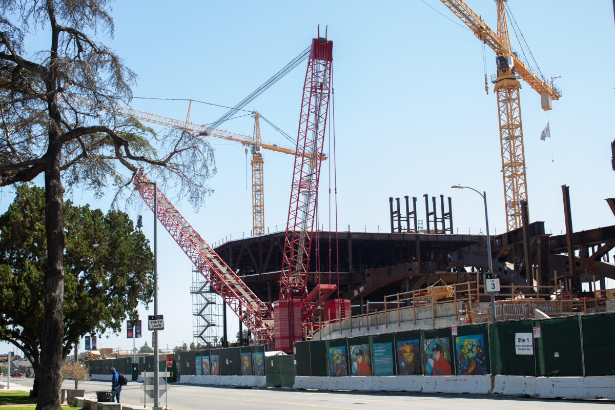 Cranes rise above a building under construction.
