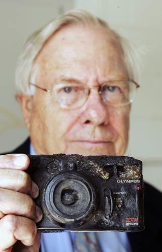 John Burrows holds one of his son's cameras, which melted in the fiery crash that killed him.