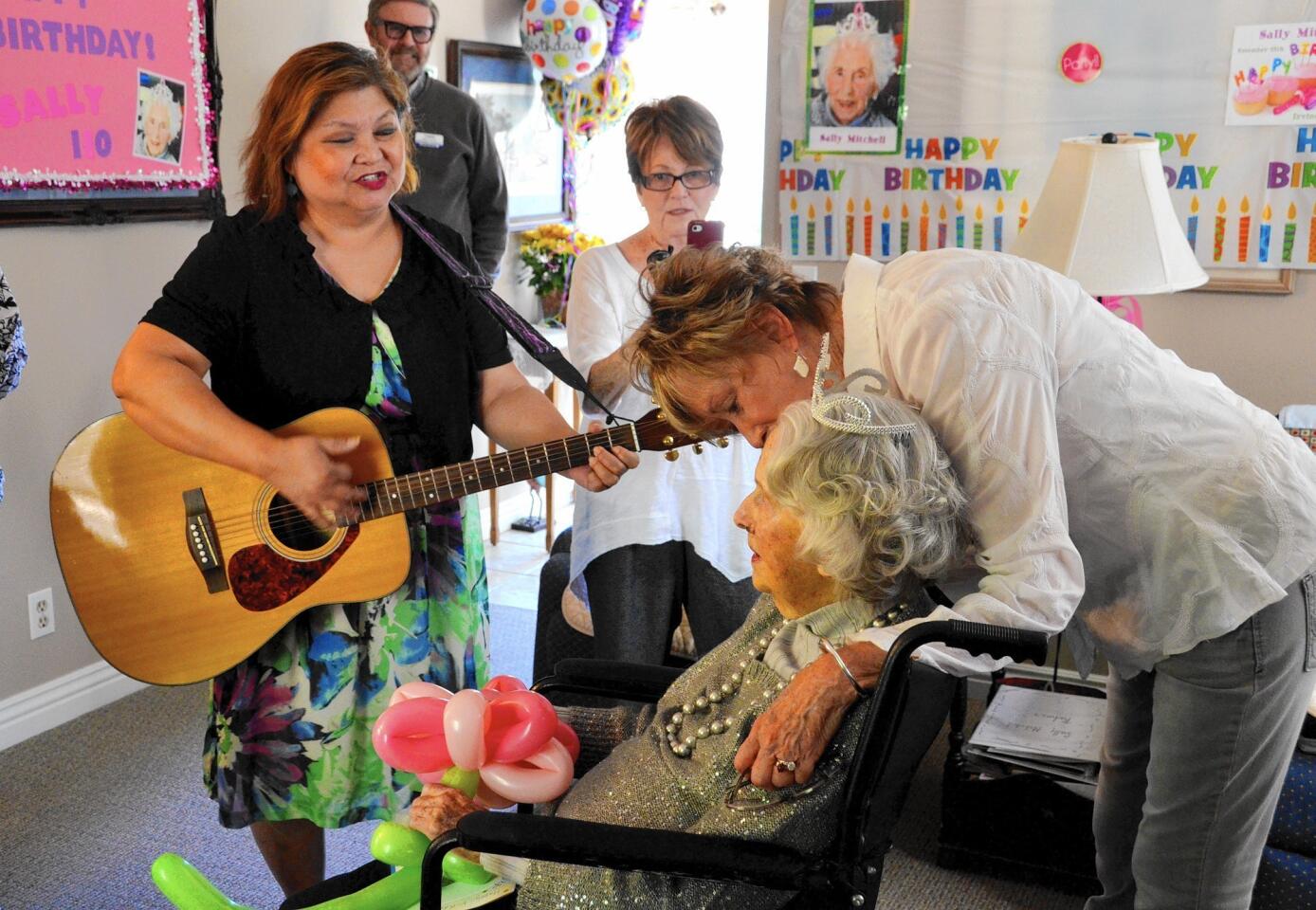 Guitarist Esther Cruz Porter serendes Sally Mitchell as part of her birthday celebration as her daughter Suzanne Becker gives her a hug.