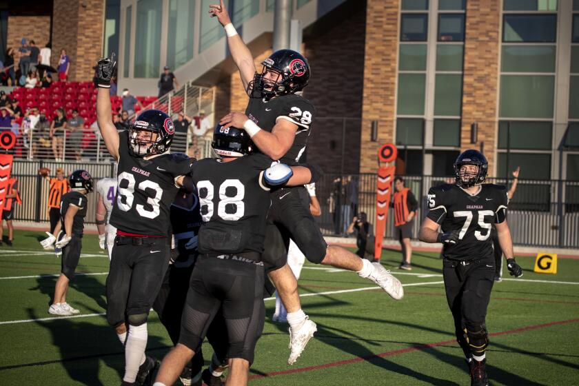 ORANGE, CALIF. -- SATURDAY, NOVEMBER 23, 2019: Chapman University players Wyatt Hardin, #83, left, James Kistner, #88, center, and Alex Baur, #75, right, celebrate Tanner Mendoza’s, #28, game-winning touchdown against Linfield, making it 68-65 in overtime at Chapman University in Orange Saturday, Nov. 23, 2019. Chapman University– the highest-rated D3 college football team in California, celebrates their first-ever NCAA playoff game as they beat Linfield 68-65 in overtime in Orange, at roughly the same time USC and UCLA were playing their annual rivalry football game at the Coliseum. (Allen J. Schaben / Los Angeles Times)