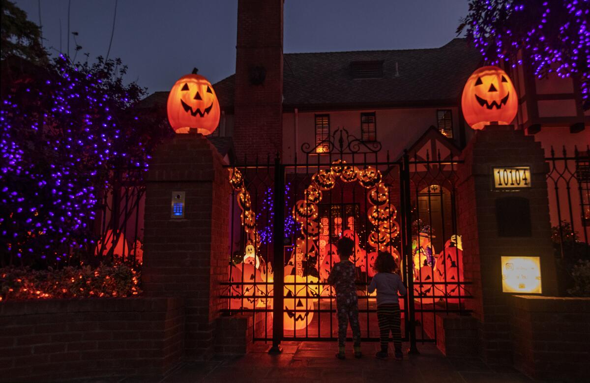 Two children look through the gates of a home decorated for Halloween