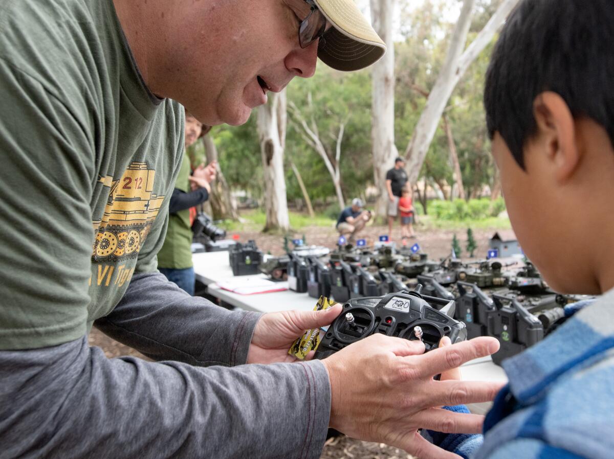 A member of the Irvine RC Tank club explains a remote control to Wesley Tran.