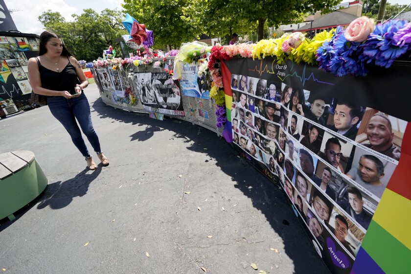 A visitor looks over a display with the photos and names of the 49 victims that died at the Pulse nightclub memorial Friday, June 11, 2021, in Orlando, Fla. Saturday will mark the fifth anniversary of the mass shooting at the site. (AP Photo/John Raoux)