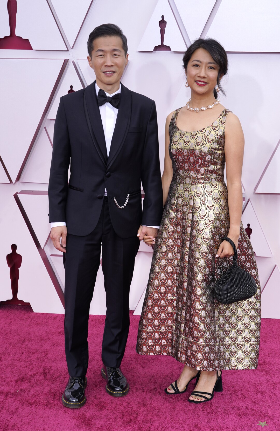 Lee Isaac Chung in a dark suit and Valerie Chung in a metallic ankle-length dress  