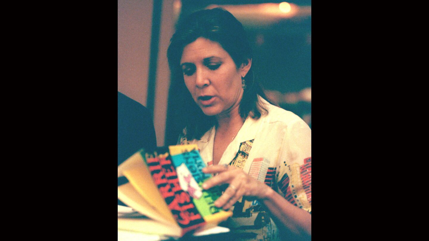 Carrie Fisher leafs through her novel "Delusions of Grandma" before speaking at the Los Angeles Times' annual authors luncheon in 1994.
