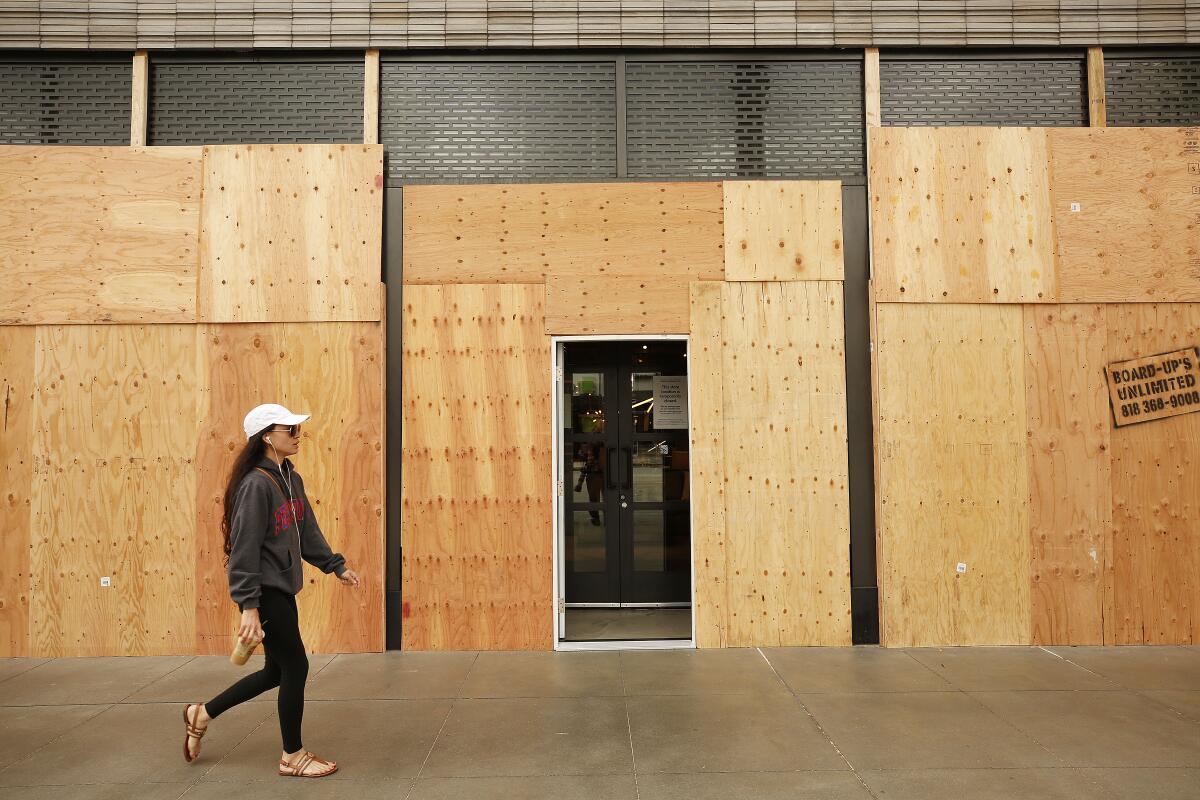 Hillary Mastrosimone walks past a boarded-up West Elm store on Colorado Boulevard in Pasadena in April.