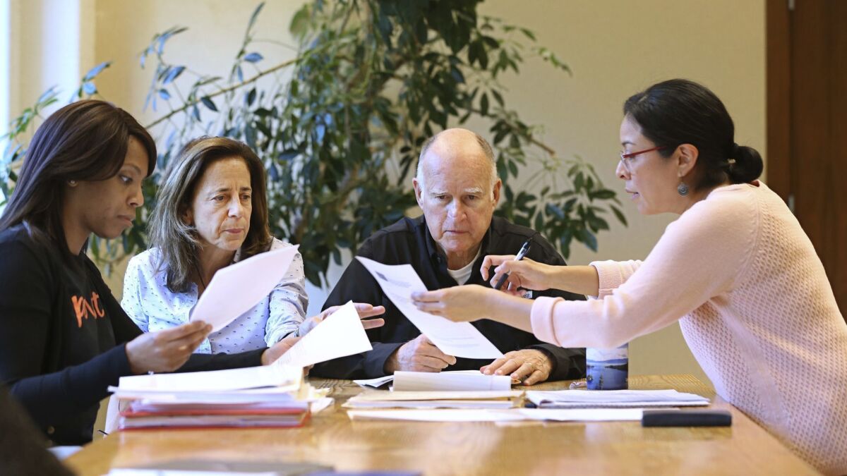 Gov. Jerry Brown reviews legislation with his wife, Anne Gust Brown, second from left and staffers Camille Wagner, left, Graciela Castillo-Krings at his Capitol office on Sunday.