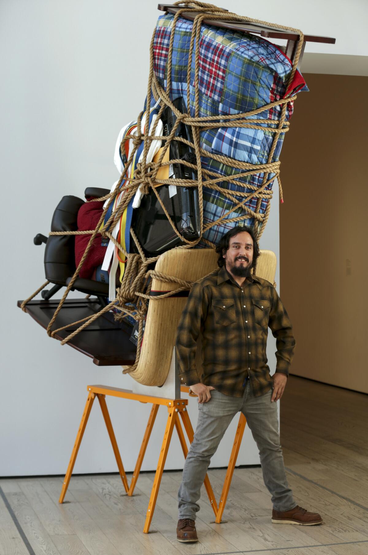 Artist Camilo Ontiveros stands before "Temporary Storage: The Belongings of Juan Manuel Montes" at LACMA. (Irfan Khan / Los Angeles Times)