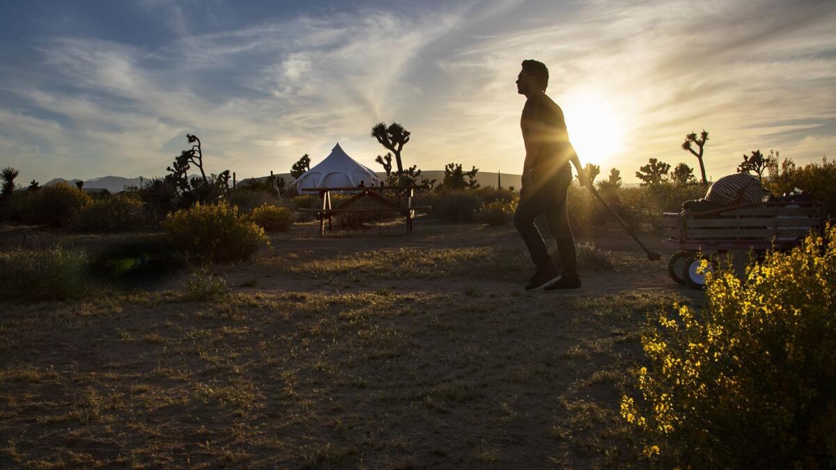 Jose Sanchez-Castro of Pasadena pulls his luggage in a wagon along a dirt trail upon arriving at Lazy Sky Retreat in Joshua Tree.