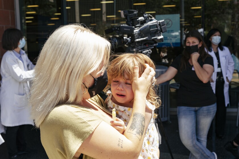 A small girl cries while being held by her mother.