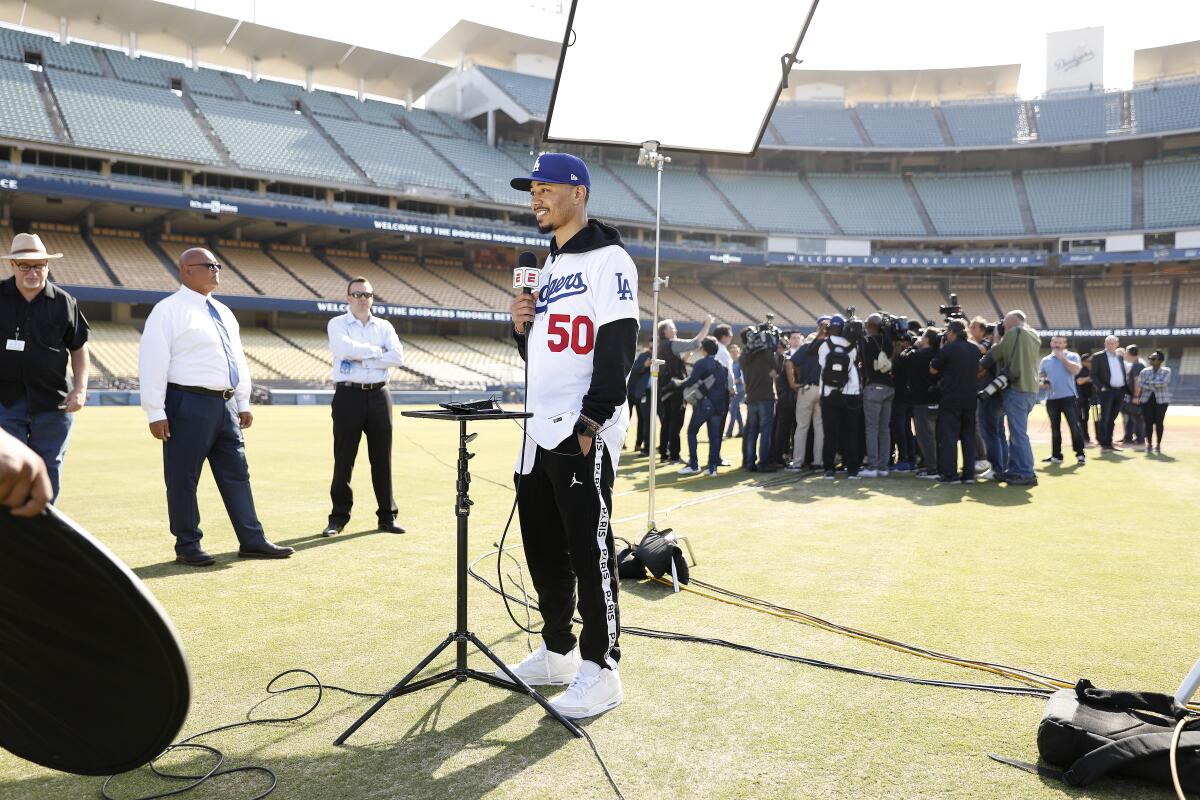 Mookie Betts, left, is interviewed on camera as his teammate David Price is swarmed by members of the press, in background, after they are both introduced as the newest Dodgers at Dodger Stadium during a press conference on Wednesday.