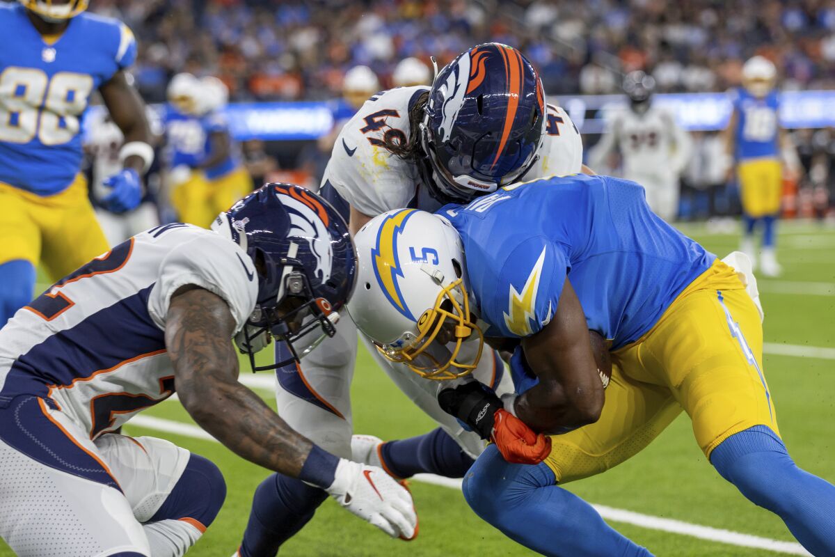 The Chargers' Joshua Palmer (5) runs after a catch and is about to make helmet-to-helmet contact as Broncos defenders chase him.